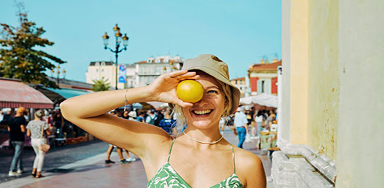 زنی با تاپ و کلاهی به سر که یک پرتقال در دست دارد